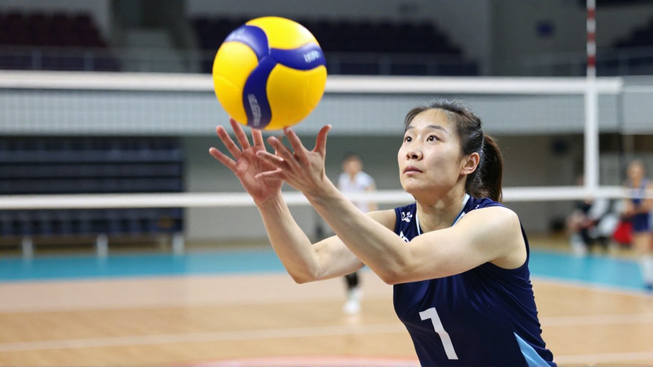 A female volleyball player makes improper hand contact with the ball during a competitive match.