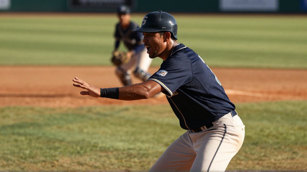 A dirt-stained baseball shortstop shouts intense commands while positioned on a sunny Dominican Republic infield.
